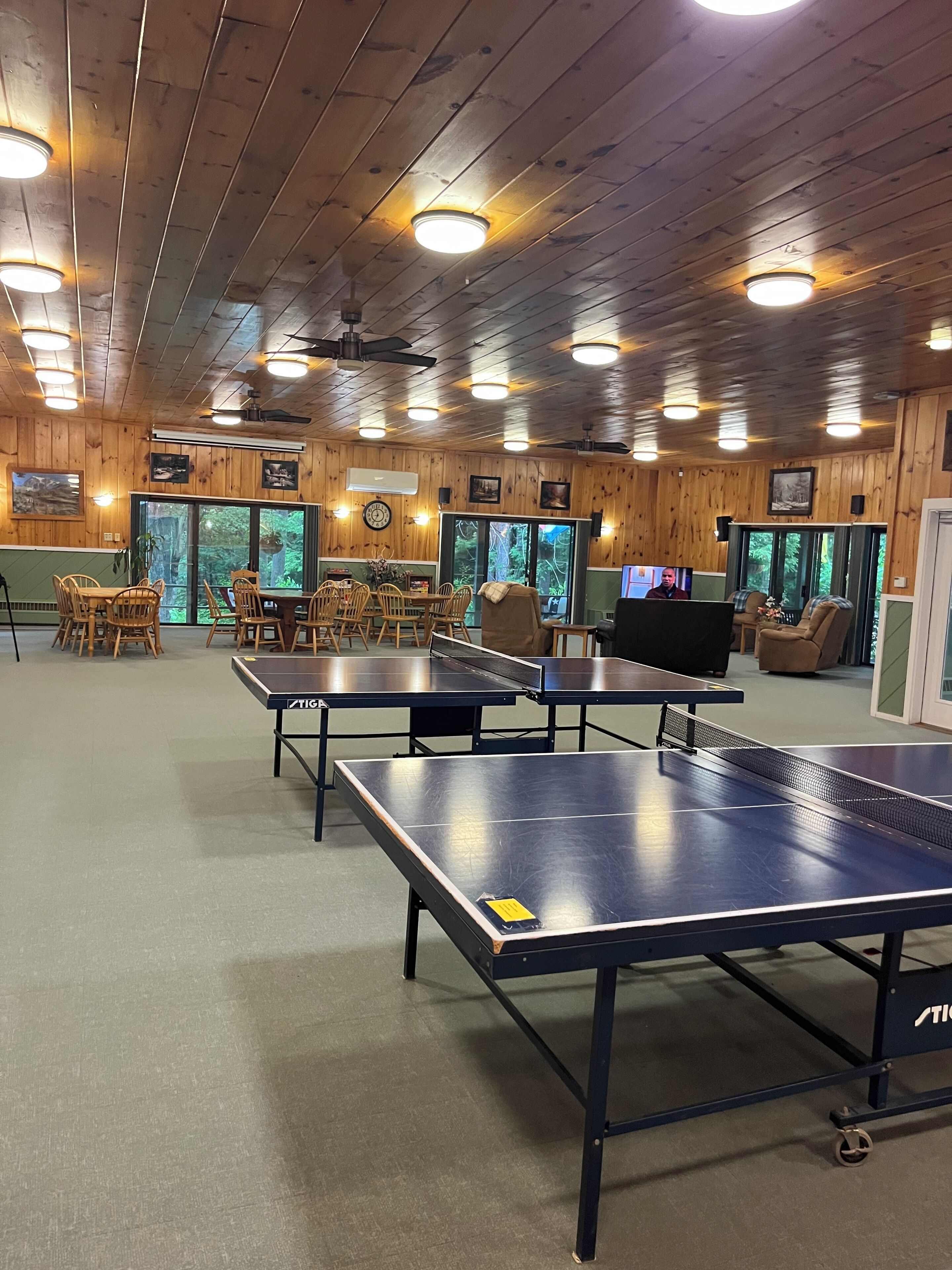Une pièce aux murs en bois, dotée de ventilateurs de plafond et d’une table de ping-pong.