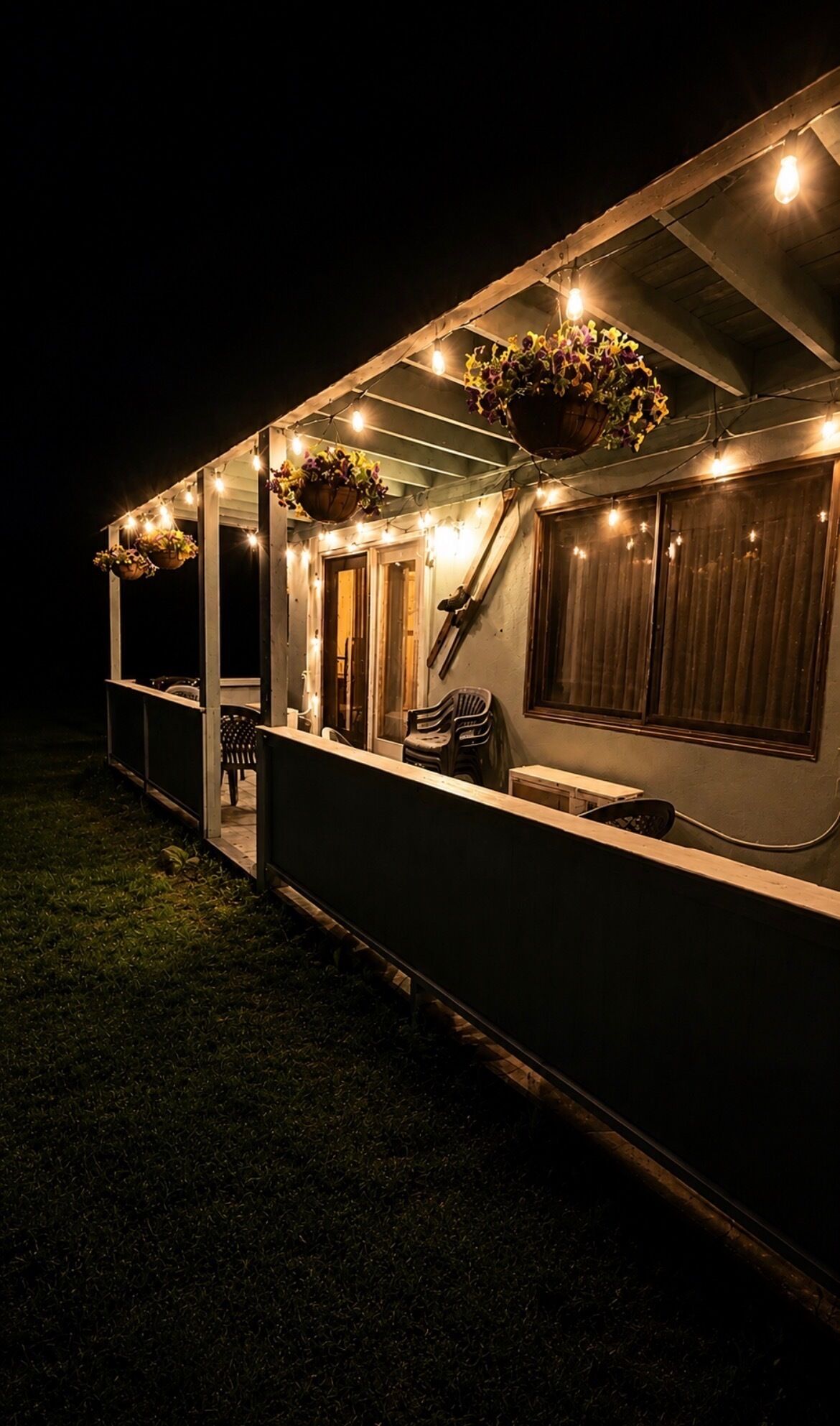 A covered outdoor area with hanging flower baskets and string lights.
