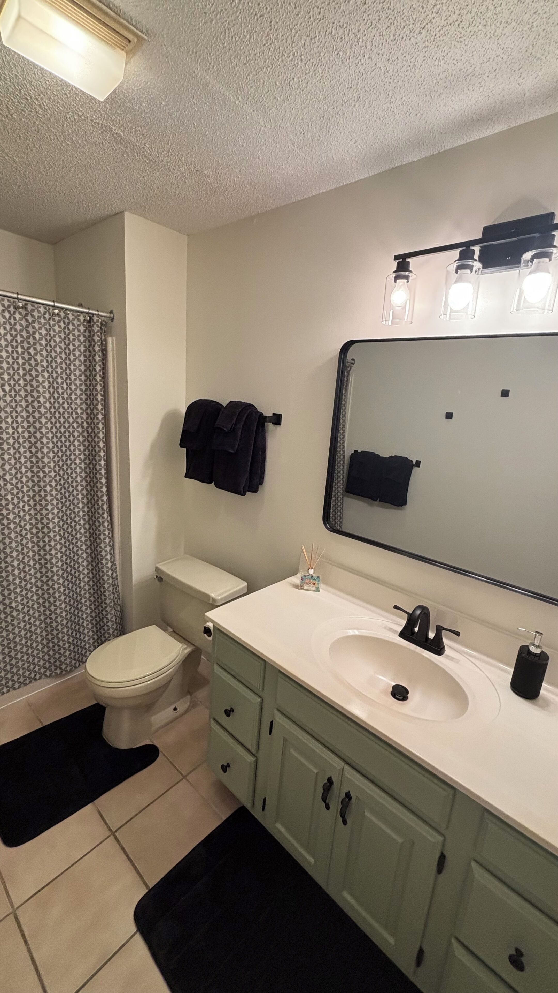 A bathroom with a toilet, sink, mirror, and shower curtain.