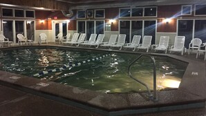 Ein überdachter Swimmingpool mit mehreren Liegestühlen und einem Rettungsschwimmerstand.