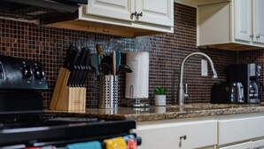 Une cuisine équipée d’une cuisinière, d’un bloc à couteaux, d’une râpe et d’une machine à café.