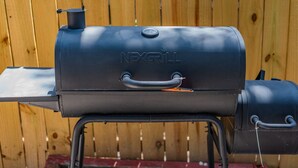 A black NEXGRILL barbecue grill with a handle and a lid, set against a wooden fence background. - 4BR Family Retreat with Game Room, Sunroom & Huge Backyard (San Antonio)