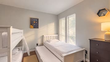Ein Schlafzimmer mit Etagenbetten, einem Nachttisch, einer Kommode, einer Lampe und einem Wandbild.