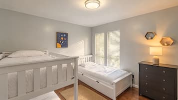 Een slaapkamer met twee bedden, een dressoir, een lamp en een kunstwerk aan de muur.