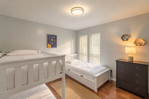 Un dormitorio con dos camas, un aparador, una lámpara y una obra de arte en la pared.