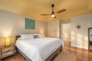 A bedroom with a bed, bedside lamps, a ceiling fan, a door, and a wall-mounted plant. - 4BR Family Retreat with Game Room, Sunroom & Huge Backyard (San Antonio)