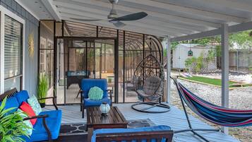A covered outdoor patio with a blue sofa, a hanging chair, and a hammock.