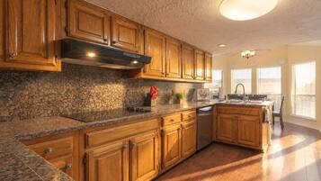 A kitchen with wooden cabinets, granite countertops, a built-in oven, and a dishwasher.