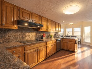 Una cocina con armarios de madera, encimeras de granito, horno empotrado y lavavajillas.