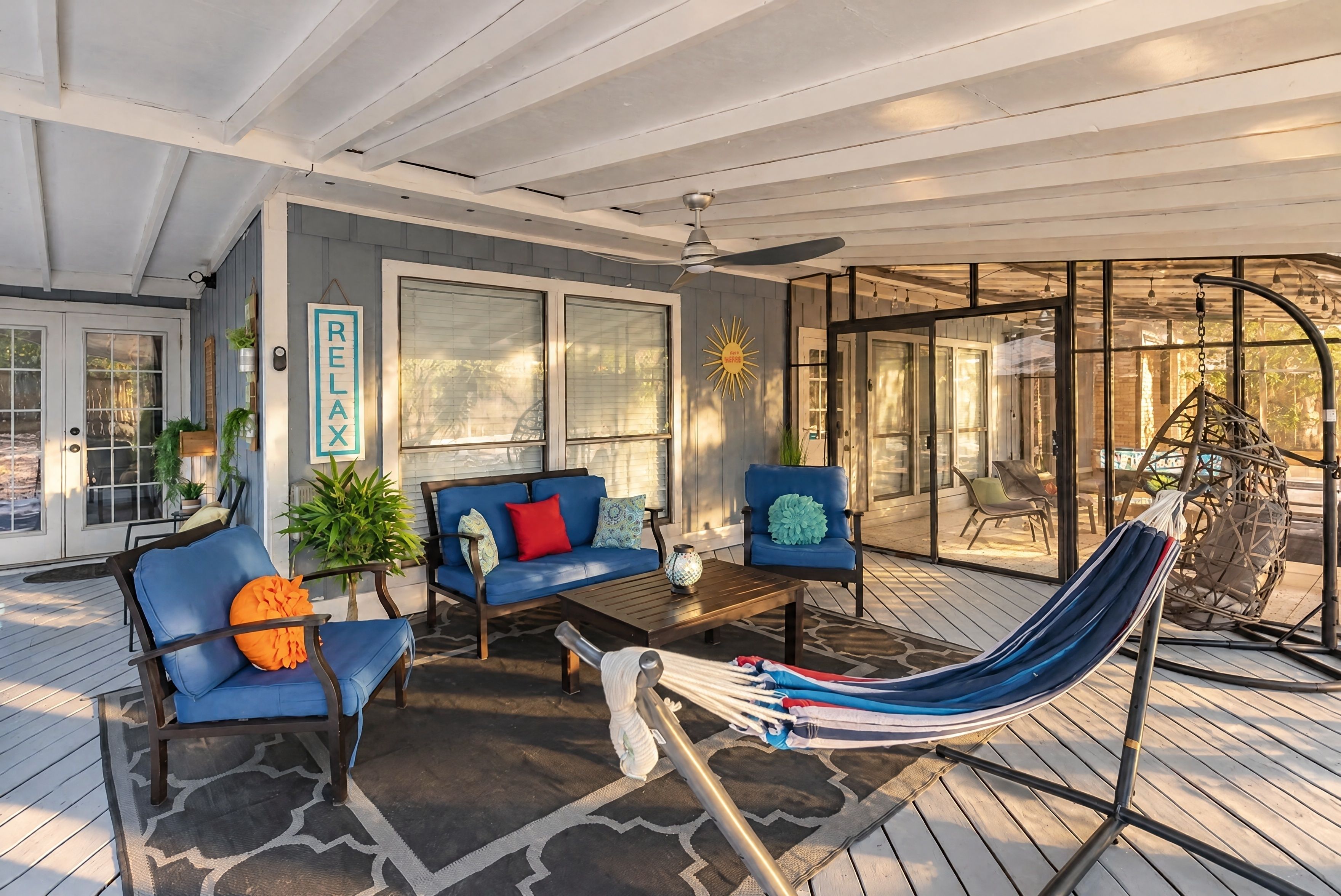Un espace extérieur aménagé, abrité, avec un hamac, des canapés bleus et une table basse.