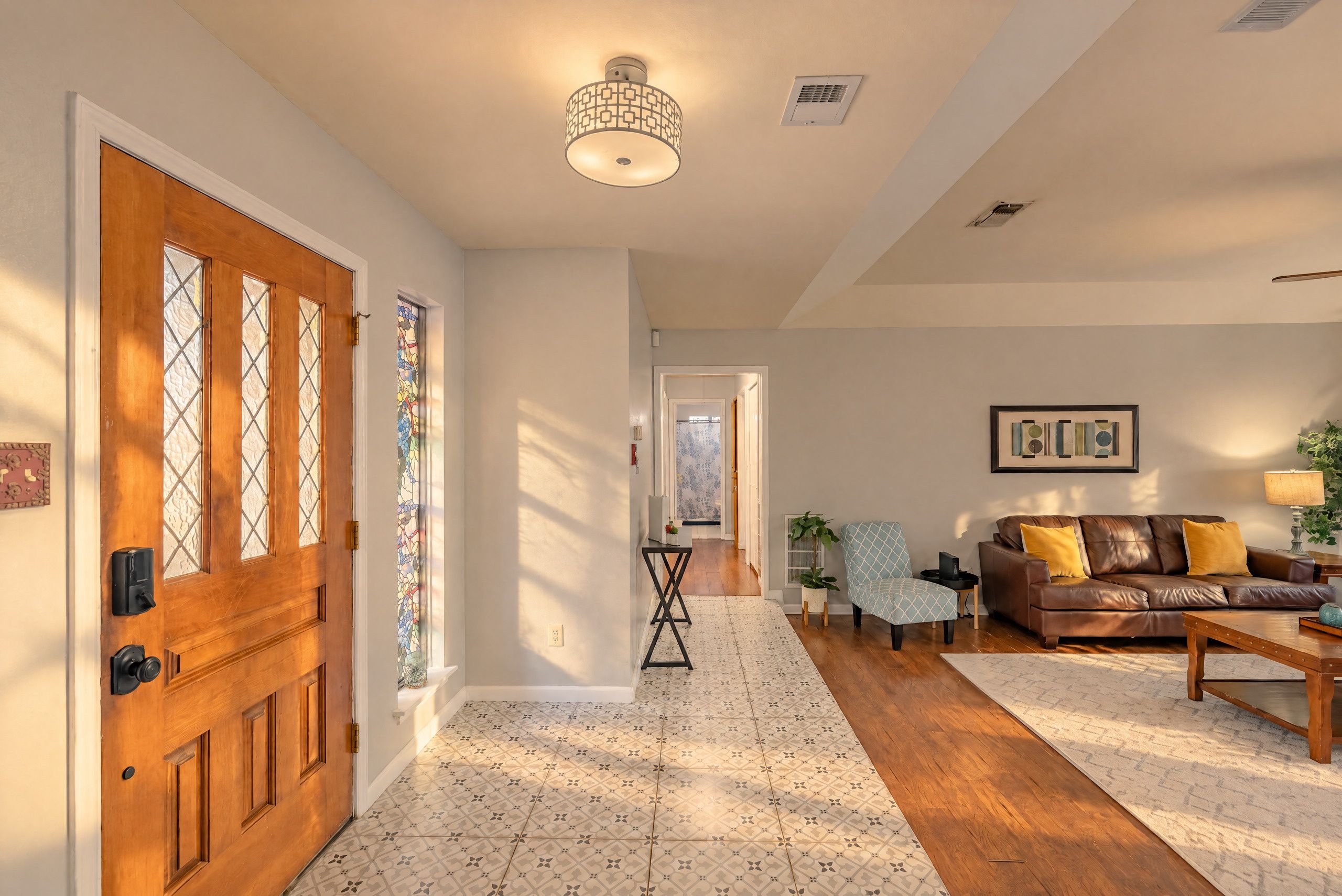 A spacious living room with a brown leather sofa, a patterned rug, and a wooden coffee table.