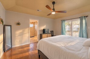 A bedroom with a bed, a ceiling fan, a TV on a cabinet, and a window with curtains. - 4BR Family Retreat with Game Room, Sunroom & Huge Backyard (San Antonio)
