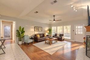 A spacious living room with hardwood flooring, two sofas, a coffee table, and a ceiling fan.