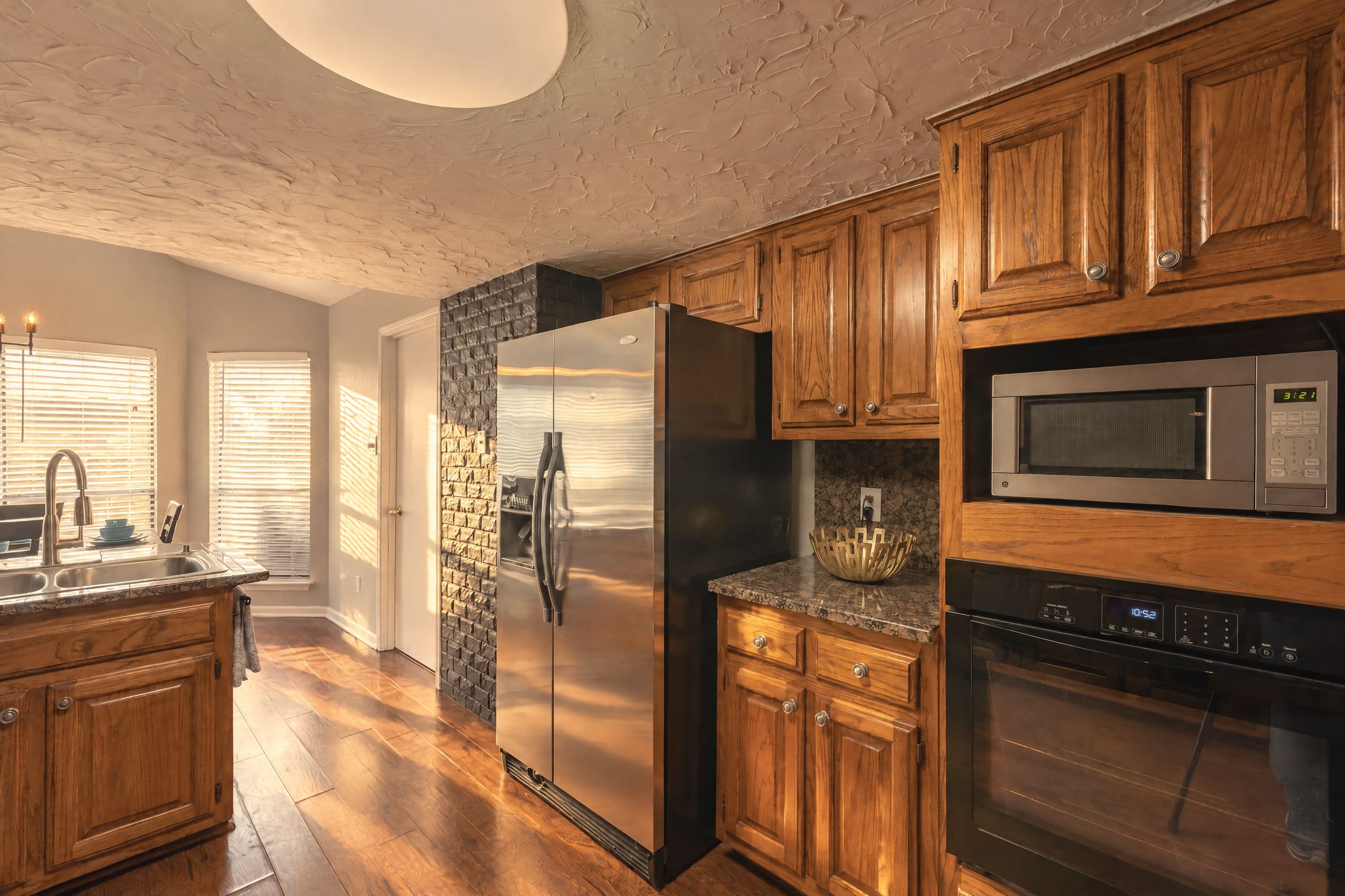 Une cuisine avec des meubles en bois, un réfrigérateur en acier inoxydable, un four à micro-ondes et un four traditionnel.