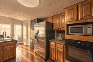 Una cocina con armarios de madera, un refrigerador de acero inoxidable, un microondas y un horno.