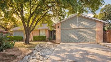 A residential building with a garage, stone pathway, and a tree in the yard.