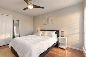Un dormitorio con cama, mesita de noche, espejo y ventilador de techo.