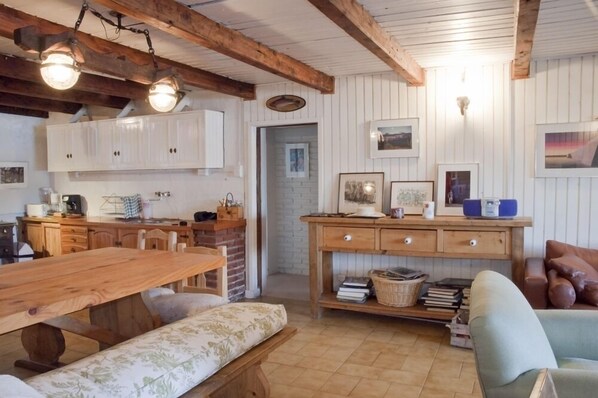A cozy room with a wooden dining table, a bench, a sofa, and a wooden cabinet with drawers.