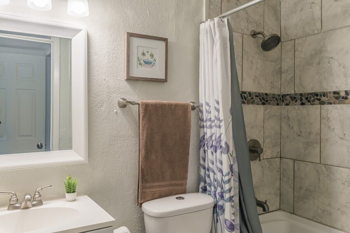 A bathroom with a white sink, a toilet, a shower with a glass door, and a framed picture on the wall.