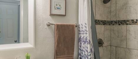 A bathroom with a white sink, a toilet, a shower with a glass door, and a framed picture on the wall.