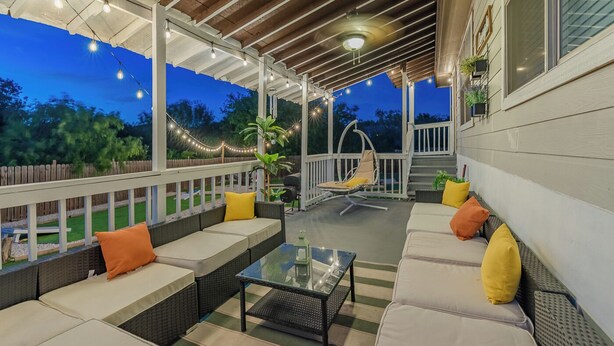 An outdoor patio with wicker furniture, string lights, and a view of the backyard.