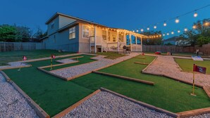 A house with a covered porch and a yard with a mini-golf setup.