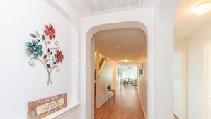 A hallway with a decorative metal flower wall art and a sign that says "In all things WE GIVE THANKS".