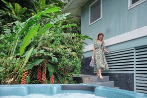 Eine Frau in einem gemusterten Kleid geht eine Treppe neben einem Pool mit tropischen Pflanzen hinunter.