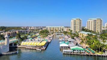 A marina with boats docked, a waterfront restaurant, and high-rise hotels in the background.