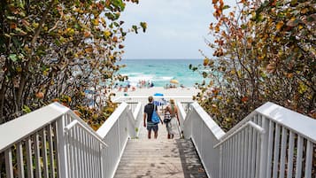 A wooden staircase leading to a beach with people and umbrellas.