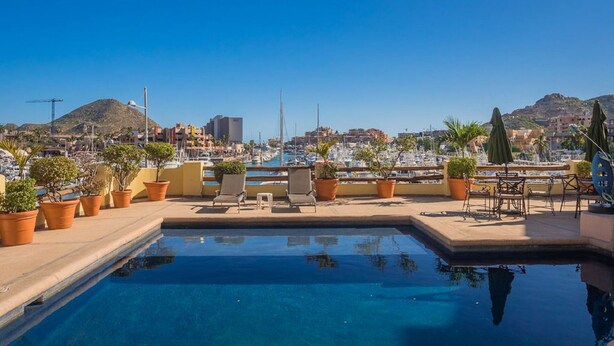 A rooftop pool with potted plants and outdoor furniture, overlooking a marina and coastal town. - Stunning Marina views, best location in Cabo! (Cabo San Lucas)