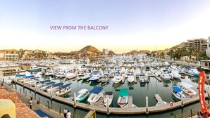 A marina filled with boats, a mountainous backdrop, and buildings in the distance. - Stunning Marina views, best location in Cabo! (Cabo San Lucas)