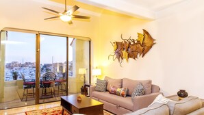 A living room with a sofa, coffee table, and a decorative wall piece. - Stunning Marina views, best location in Cabo! (Cabo San Lucas)
