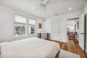 A bedroom with a bed, a desk, a chair, and a ceiling fan. - Historic Beach Cottage - Steps to Beach & Dining (Saint Simons Island)