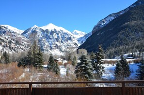 Un paysage montagneux aux sommets enneigés, avec une cabane au premier plan.