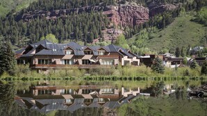 Een groot, meerijlaags hotel met uitzicht op een spiegelglad meer, omgeven door beboste heuvels.