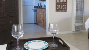 A dining area with a tray holding two wine glasses and a plate, a kitchen visible through an open door, and a motivational quote on the wall. - "Balboa Beach Escape"  Steps to Beach and Bay A/C + Garage Parking (Newport Beach)
