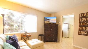 A living room with a beige couch, a television on a wooden stand, a small table with a clock, and a wall with motivational quotes. - "Balboa Beach Escape"  Steps to Beach and Bay A/C + Garage Parking (Newport Beach)