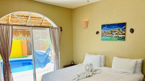 Ett hotellrum med en säng, en tavla och utsikt över en pool och ett utomhusområde.