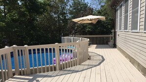 Ett trädäck med en swimmingpool, omgivet av ett vitt staket.