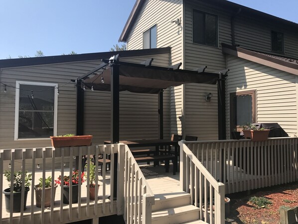 A house with a covered patio area, outdoor seating, and potted plants.