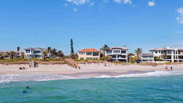 A beachfront property with multiple houses, a sandy beach, and the ocean.