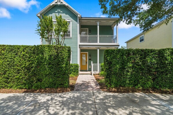 A two-story house with a front porch, a small balcony, and a well-maintained hedge. - Patriot's Playa: Private Pool, Golf, Water Park, Near Disney (Kissimmee)