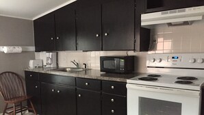 A kitchen with dark cabinets, a white stove, a microwave, and a sink. - ' Experience ' The History In Downtown Gettysburg! - 2nd floor (Gettysburg)