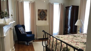 A bedroom with a bed, a chair, a radiator, a painting, and a wardrobe. - ' Experience ' The History In Downtown Gettysburg! - 2nd floor (Gettysburg)