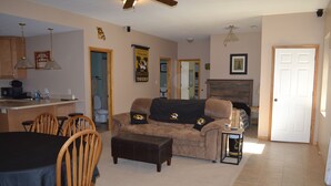 A living room with a sofa, ottoman, and a dining area with chairs and a table. - Sander Ridge - 40 wooded acres (Columbia)
