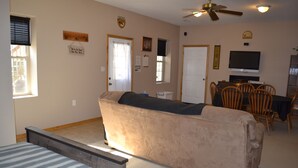 A living room with a sofa, a dining table with chairs, a television, and a ceiling fan. - Sander Ridge - 40 wooded acres (Columbia)