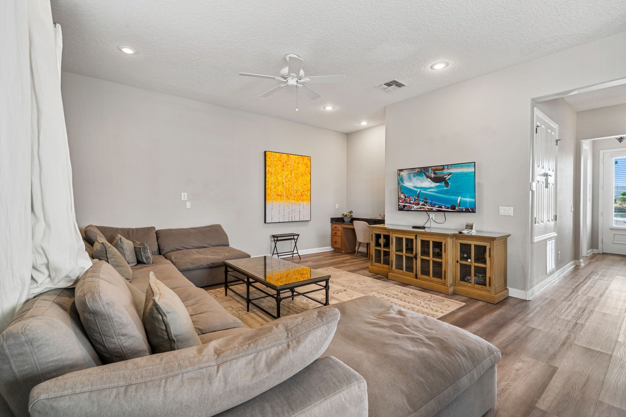 A modern living room with a sectional sofa, a coffee table, a TV, and a cabinet.