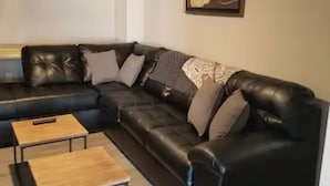 A modern living room with a sectional sofa, two coffee tables, and a framed artwork on the wall. - The Carter's Wildwood Rentals-  Master Suite #3 (Wildwood)