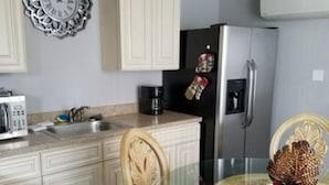 A kitchen with white cabinets, a stainless steel refrigerator, a coffee maker, and a decorative pine cone on the table. - The Carter's Wildwood Rentals-  Master Suite #3 (Wildwood)